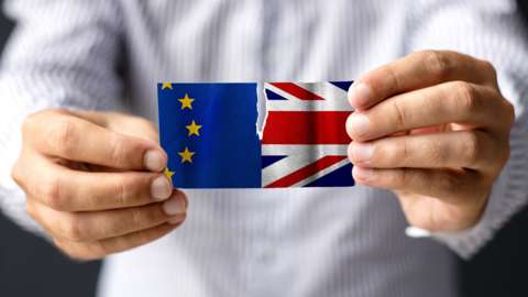 Man ripping EU and Union Jack flag in half.