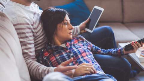 Couple lying on couch watching television