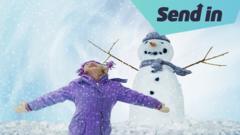 Child looks up at snow next to snowman