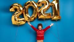 A child stands beneath 2021 balloons