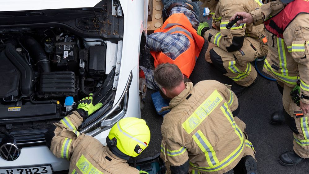 Feuerwehrleute arbeiten daran, einen Aktivisten der "Letzten Generation" von der A 100 in Berlin zu lösen.