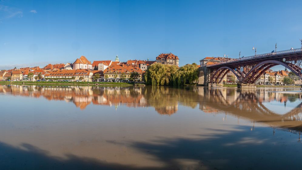 Blick auf die Stadt Maribor und den Fluss Drau mit einer Brücke, die über den Fluss führt: Hier lässt sich Traumurlaub machen.